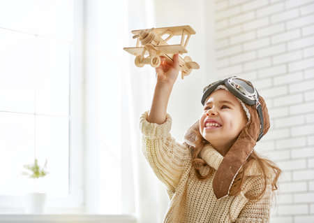 happy child girl playing with toy airplane. the dream of becoming a pilotの写真素材