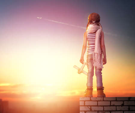 a child plays with a toy airplane in the sunset and dreams of becoming a pilotの写真素材