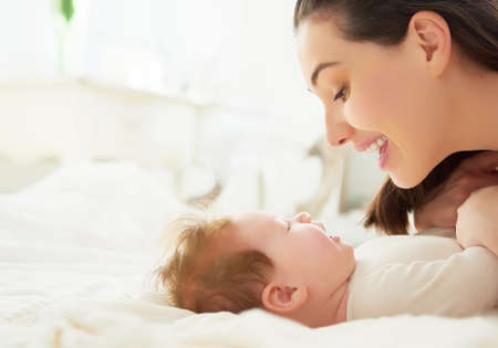 happy family. mother playing with her baby in the bedroom.