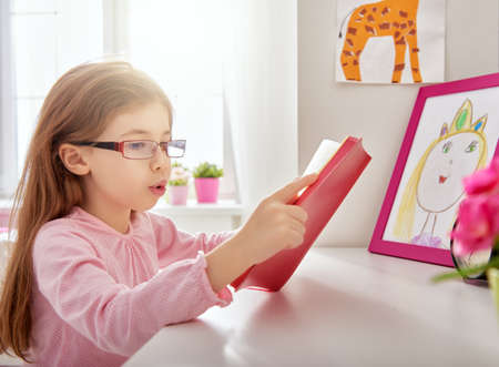 cute child girl reading a book at home. girl learning at the desk. home study