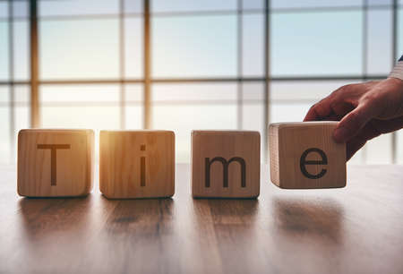 the concept of time. hand men in business suit holding the cubes which the written word time.