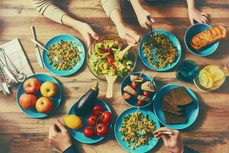 Top view of family having dinner together sitting at the rustic wooden table. Enjoying  family dinner together.の写真素材