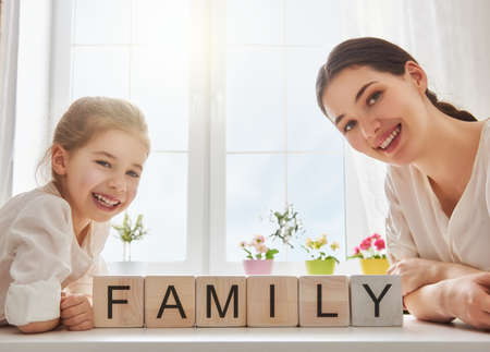Happy loving family playing with blocks and having fun. Blocks have letters. Mother and her daughter lay out cubes and word family.の写真素材