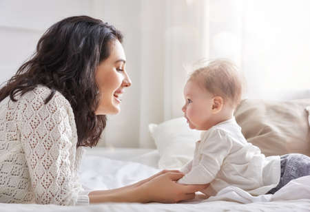 happy loving family. mother playing with her baby in the bedroom.の写真素材