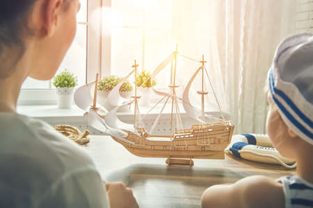 Mother and her child making model ship. Dreams of sea, adventures and travel.の写真素材