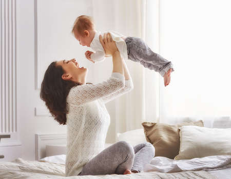 happy loving family. mother playing with her baby in the bedroom.の写真素材