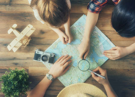 Go on an adventure! Happy family preparing for the journey. Mom, dad and daughter study the map and...