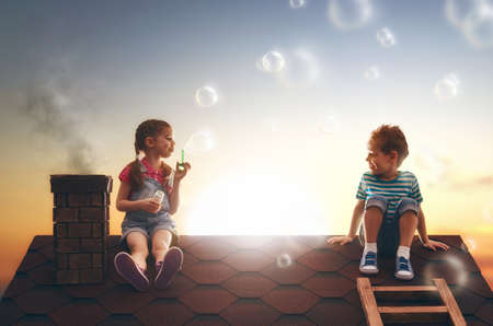 happy childhood! boy and girl playing on the roof. child blowing soap bubbles.の写真素材