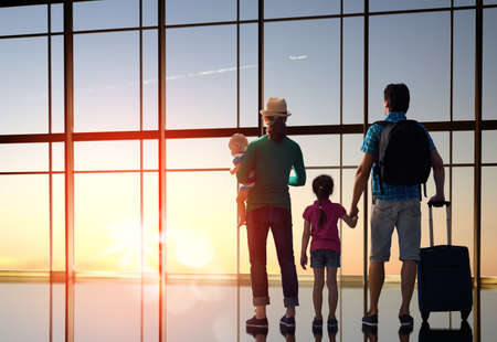 Happy family with children at the airport. Parents and their children look out the window at the plane.の写真素材