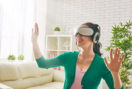 Beautiful young woman playing game in virtual reality glasses.