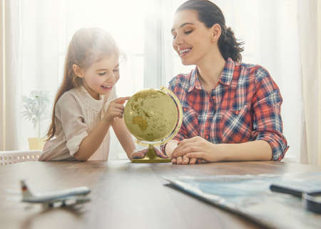 Go on an adventure! Happy family preparing for the journey. Mom, dad and daughter study the globe and choose a route of travel.の写真素材