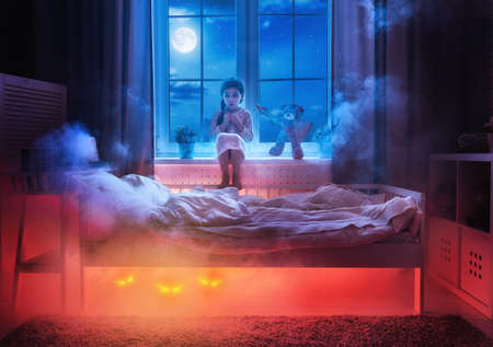 Nightmare for children. Little child girl is afraid of monsters in the dark of night. Frightened...