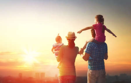 happy family at sunset. father, mother and two children daughters having fun and playing in nature....