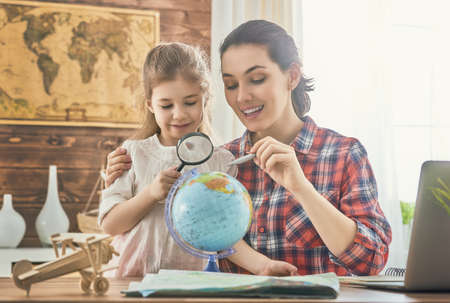 Go on an adventure! Happy family preparing for the journey. Mom and daughter study the map and...
