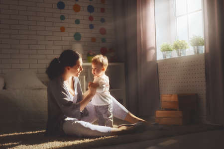 happy loving family. mother playing with her baby in the bedroom.の写真素材