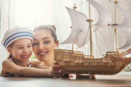 Mother and her child girl making model ship. Dreams of sea, adventures and travel.の写真素材
