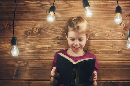 Cute little child girl reading a book.