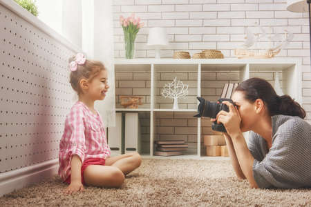 Happy loving family. Mother and her daughter child girl playing and making photo.の写真素材