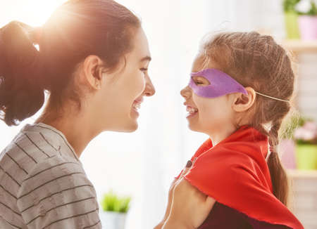 Happy family is preparing for a costume party. Mother and her child girl playing together. Girl in...