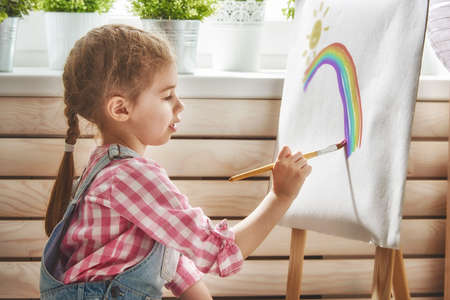 Happy little child draws paints. Sweet girl engaged in creativity.の写真素材