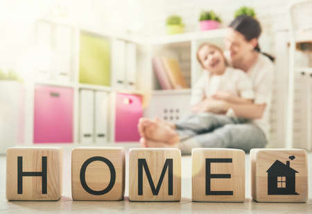 Happy loving family playing with blocks and having fun. Blocks have letters. Mother and her daughter lay out cubes and word home.の写真素材