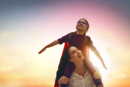 Mother and her child girl playing together. Kid in an Superhero's costume.の写真素材