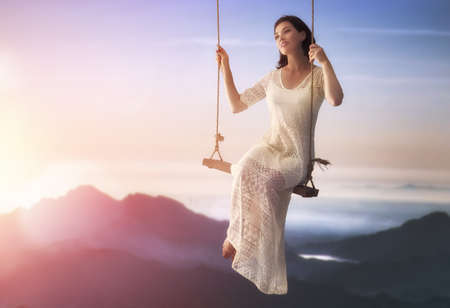 beautiful young woman on a swing on summer day outdoorsの写真素材