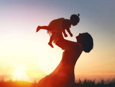 Happy loving family. Mother and her daughter baby girl playing and laughing in the summer at sunset outdoors.の写真素材