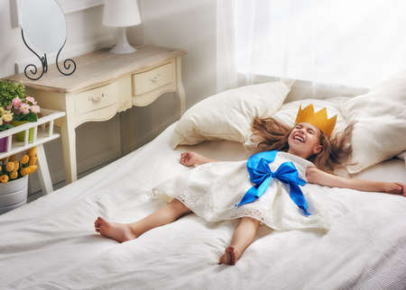 Cute little girl in a princess costume. Pretty child preparing for a costume party. Beautiful queen in gold crown.の写真素材