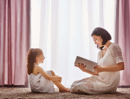 happy loving family. pretty young mother reading a book to her daughter
