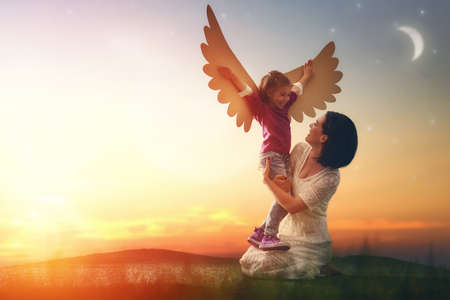 Mother and her daughter child playing together. Little girl plays in the bird. Happy loving family having fun.の写真素材