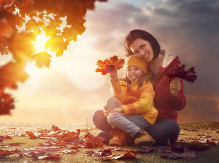Mother and her child girl playing together on autumn walk in nature outdoors. Happy loving family having fun.の写真素材