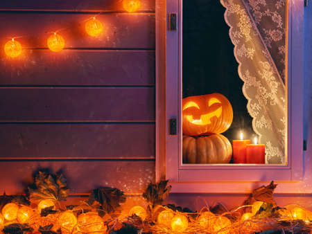 Happy halloween! The window of a house decorated for the holiday. Pumpkins, garland, candles and autumn leaves.の写真素材