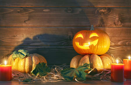 Happy halloween! Head pumpkin, candles and autumn leaves on wooden background.の写真素材
