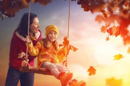 Mother and her child girl playing together on autumn walk in nature outdoors. Happy loving family having fun.の写真素材