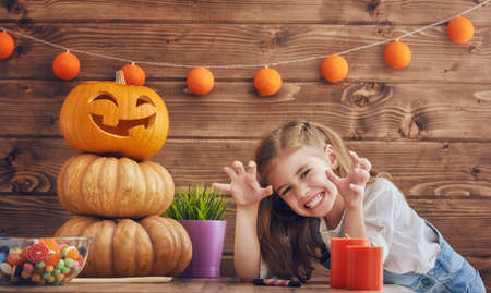 Happy halloween! Cute little child girl with carving pumpkin. Happy family preparing for Halloween.の写真素材
