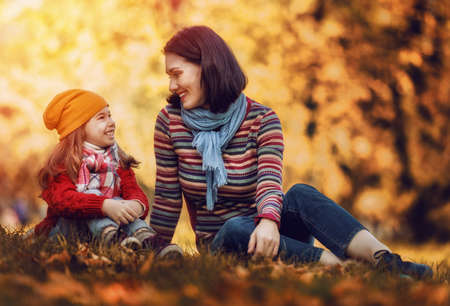 Happy family on autumn walk! Mother and daughter walking in the Park and enjoying the beautiful autumn nature.の写真素材