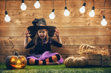 Happy Halloween! Cute little witch with a pumpkin.の写真素材