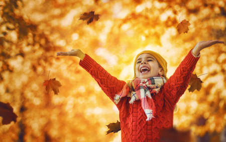 Cute little happy girl walking in autumn Park. Pretty child enjoys the beautiful autumn nature.の写真素材