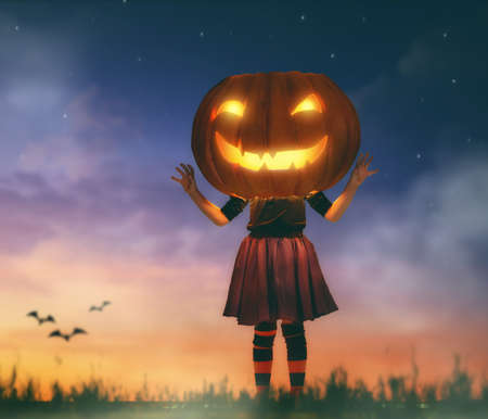 Happy Halloween! Cute little kid with a big pumpkin head outdoors.の写真素材