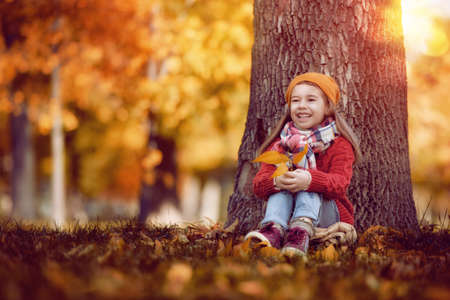 Cute little happy girl walking in autumn Park. Pretty child enjoys the beautiful autumn nature.