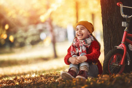 Cute little happy girl walking in autumn Park. Pretty child enjoys the beautiful autumn nature.の写真素材