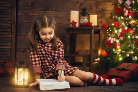 Merry Christmas! Cute little child girl writes the letter to Santa Claus.の写真素材