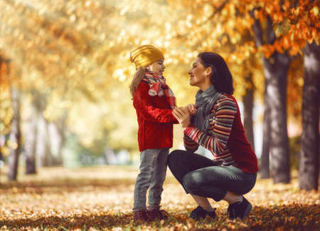 Happy family on autumn walk! Mother and daughter walking in the Park and enjoying the beautiful autumn nature.の写真素材