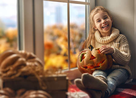Cute little child girl looking out the window after Halloween.の写真素材