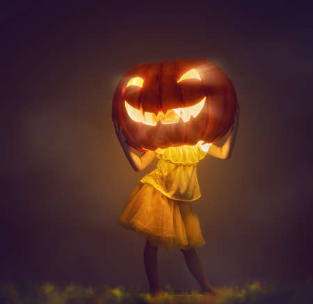 Happy Halloween! Cute little kid with a big pumpkin head.の写真素材