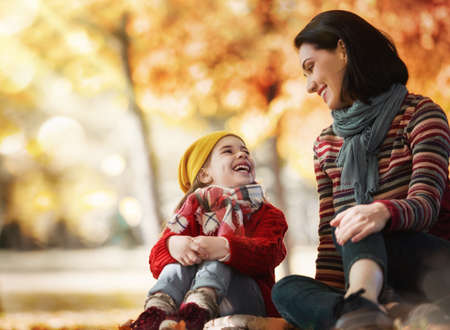 Happy family on autumn walk! Mother and daughter walking in the Park and enjoying the beautiful autumn nature.の写真素材