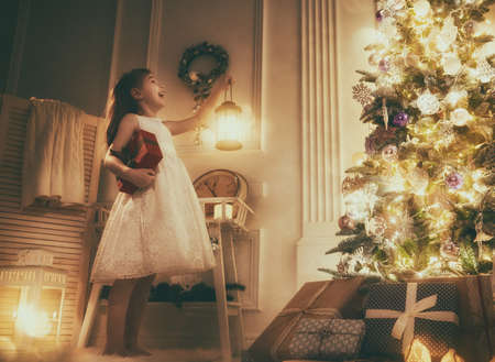 Merry Christmas and Happy Holiday! Cute little child girl with Christmas present. Kid holds a gift box.の写真素材
