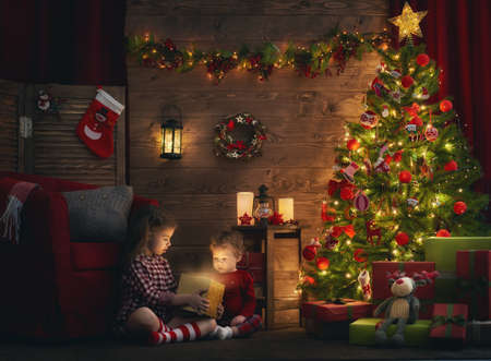 Merry Christmas and Happy Holiday! Two cute little children girls sisters with magic gift box on Christmas.の写真素材