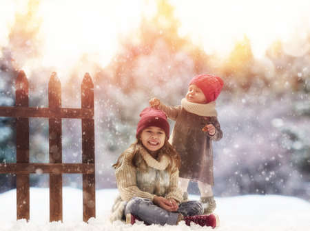 Two cute children girls playing on a winter walk in nature. Happy kids outdoors.の写真素材